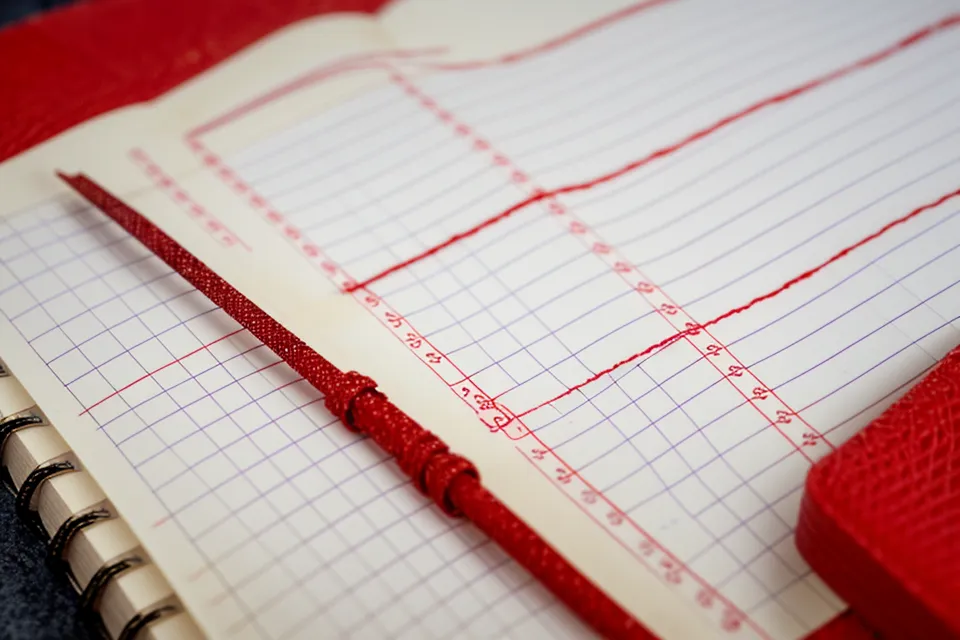 Handwritten lottery data comparison in a teacher's school notebook.